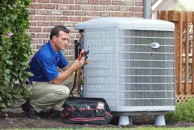 design-air-heating-and-air-conditioning-decatur-il-05 – Copy HVAC technician inspecting an outdoor air conditioning unit in Louisville, CO